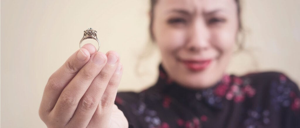 Lab-grown diamond engagement ring held by woman with a joyful smile, showcasing ethical jewelry.