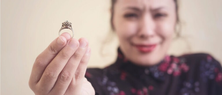 Lab-grown diamond engagement ring held by woman with a joyful smile, showcasing ethical jewelry.