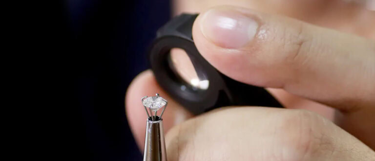 Lab-grown diamond being examined with jewelry tools for authenticity and quality.