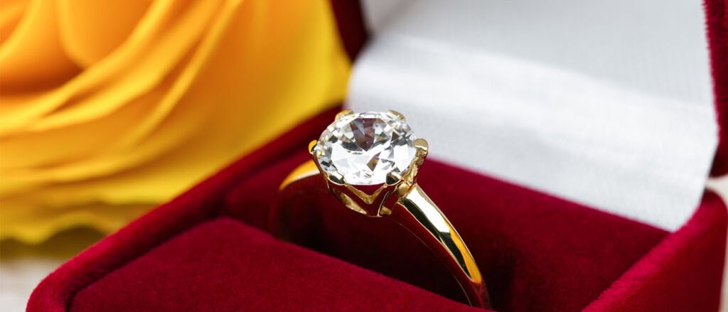 Lab-grown diamond engagement ring in elegant jewelry box with yellow flower.