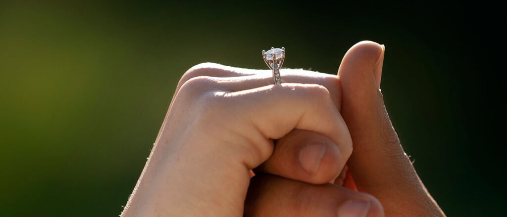 1. Close-up of a lab-grown diamond engagement ring on a person's finger.