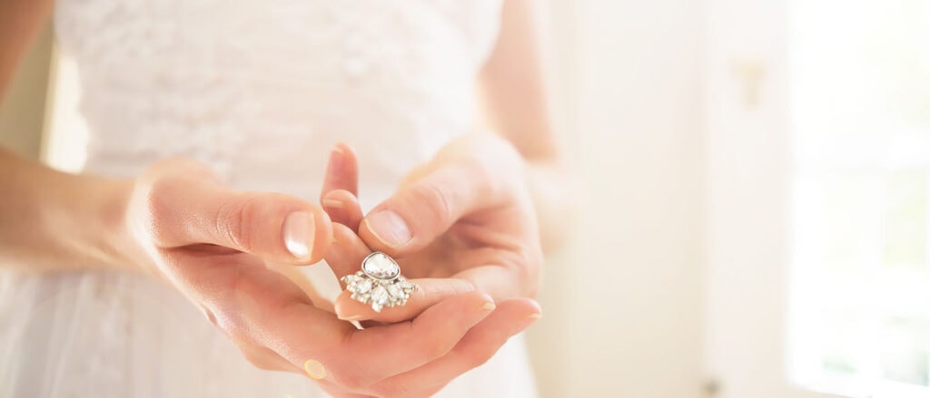 Shiny lab-grown diamond ring held by a woman, representing real stories behind sustainable diamonds.